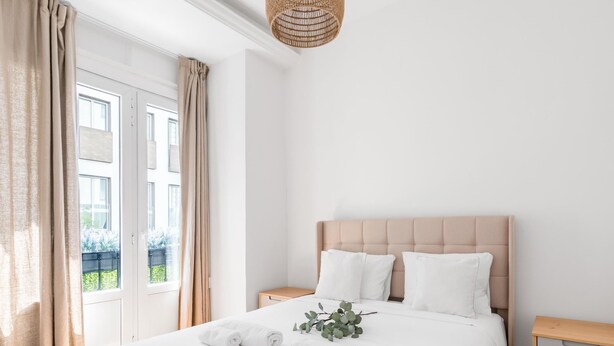 Een moderne slaapkamer met een groot bed, twee nachtkastjes en uitzicht op groen.