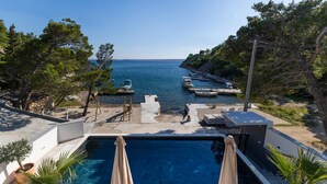 A swimming pool with a view of the sea, surrounded by trees and a dock with boats. - Lovely home in Baric Draga (Baric Draga)