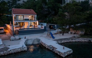 Situated by the water, this house offers a spacious outdoor area with seating and a children's play area.
