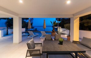 Relax on the patio with a scenic ocean view, overlooking the pool and surrounded by lush greenery.