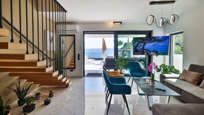 A modern living room with a staircase, a sofa, a coffee table, and a TV. - Lovely home in Baric Draga (Baric Draga)