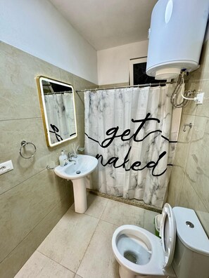 A bathroom with a sink, toilet, and shower curtain. - Shkodra Guesthouse (Shkoder)