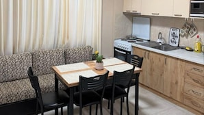 Cocina compacta con zona de comedor, que incluye un sofá, una mesa con sillas, una estufa y armarios.