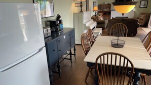 A kitchen with a refrigerator, a coffee maker, and a dining table with chairs. - Ostrander's 3 Bedroom Cottage on Rice Lake (Harwood)