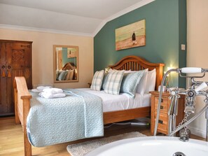 A bedroom with a wooden bed, a bedside table with a lamp, a mirror, and a painting on the wall. - 3 bedroom accommodation in Stainton, near Penrith (Stainton, near Penrith)