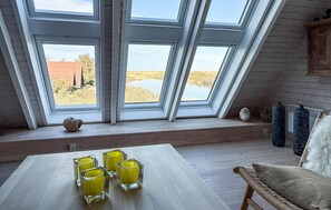 Quarto com uma mesa, quatro copos e vista para um campo através de claraboias.
