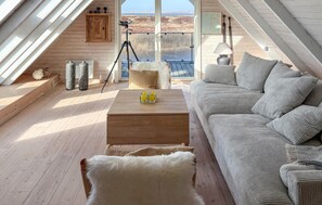 Um quarto de loft acolhedor com piso de madeira, um sofá, uma mesa de centro e um telescópio.