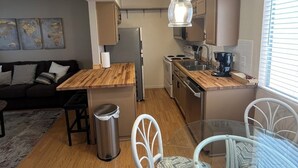 A compact living space with a kitchenette, a dining area with a glass table, and a sofa in the living area. - Cute Condo in Downtown Area! (Lake Havasu City)