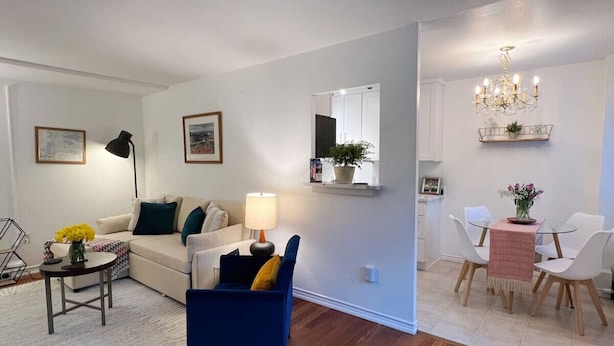 A modern living room with a sofa, a blue armchair, a coffee table, and a dining area with a table and chairs.