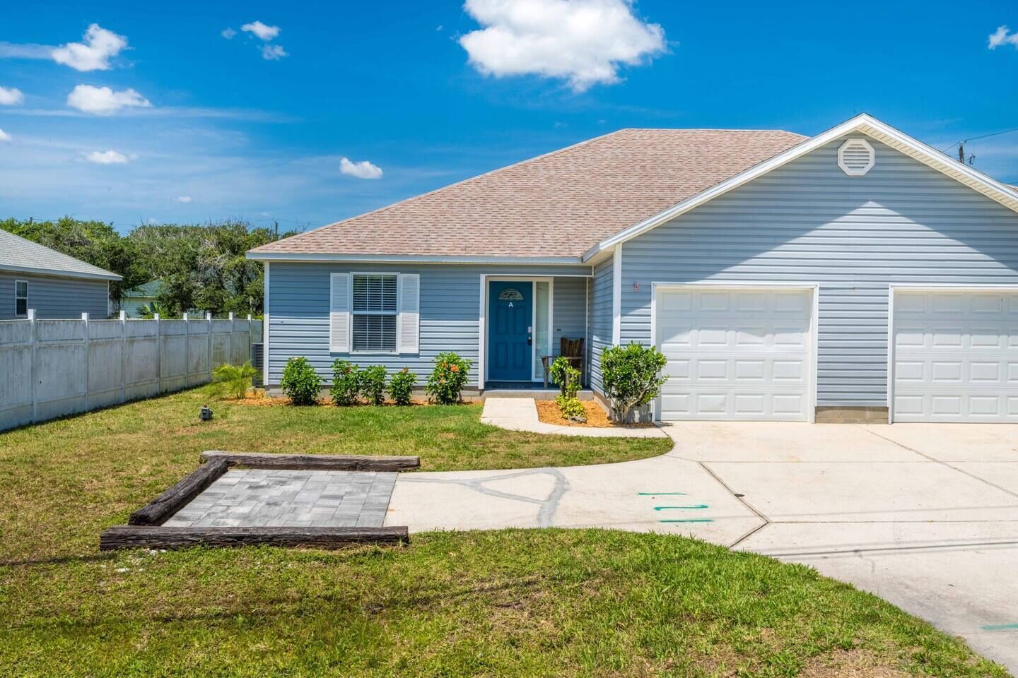Une maison d’habitation de plain-pied avec un garage à l’avant, un petit jardin devant et une allée pavée.