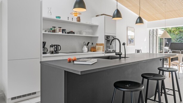 A modern kitchen with a central island, black bar stools, and pendant lighting. - 3 bedroom lovely home in Gilleleje (Gilleleje)