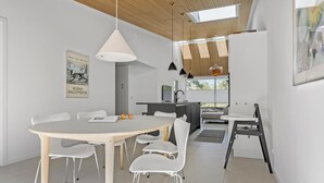 A modern kitchen with a central island, white chairs, and a dining table. - 3 bedroom lovely home in Gilleleje (Gilleleje)