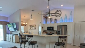 Eine moderne Küche mit Bar, Essbereich und Wohnzimmer mit Sofa.