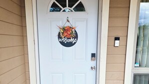Una puerta blanca con un letrero que dice 'welcome' y un felpudo.