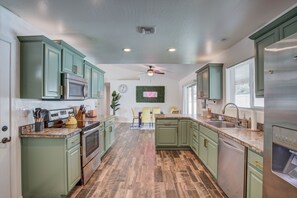 Une cuisine avec des armoires vertes, des appareils en acier inoxydable et un plancher en bois.