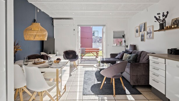 En moderne opholdsstue med spiseplads, sofa og køkken.