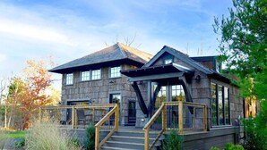 A modern two-story house with a stone facade, large windows, and a covered porch with wooden railings. - Home w/ 2-Story Windows + Studio | 70+ Amenities (Richmond)