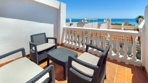 A balcony with wicker furniture and a view of the sea.