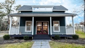 A two-story house with a porch, a front door, and a small window above the door.
