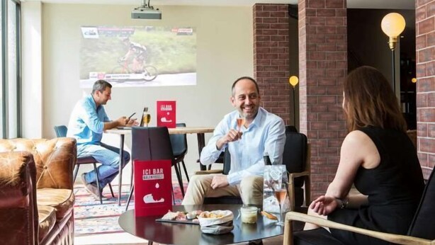 Un interior moderno con una pared de ladrillo, una pantalla de proyección y una mesa con comida y bebidas.