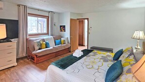 Un dormitorio con cama, sofá, escritorio y ventana.