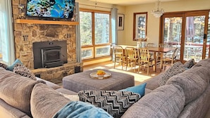 Amplia sala de estar con chimenea de piedra, televisor grande y techo alto con ventilador.