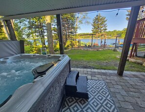 A hot tub with a view of a lake and a deck area with outdoor furniture. - Lakefront - Hot Tub • Kayaks • Fire Pit • Sauna • Jacuzzi • Games • Sleeps 14 (Tobyhanna)