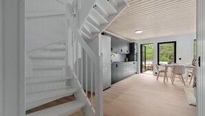 Ett modernt kök med grå skåp, en inbyggd ugn och en matplats med ett bord och stolar.