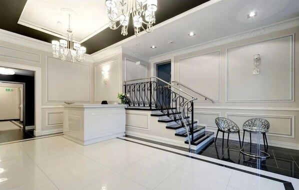 Experience the grandeur of our lobby, featuring a grand staircase, minimalist reception desk, and elegant chandelier.