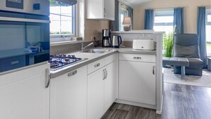 Una cocina moderna con armarios blancos, una estufa a gas, una cafetera y un tostador.