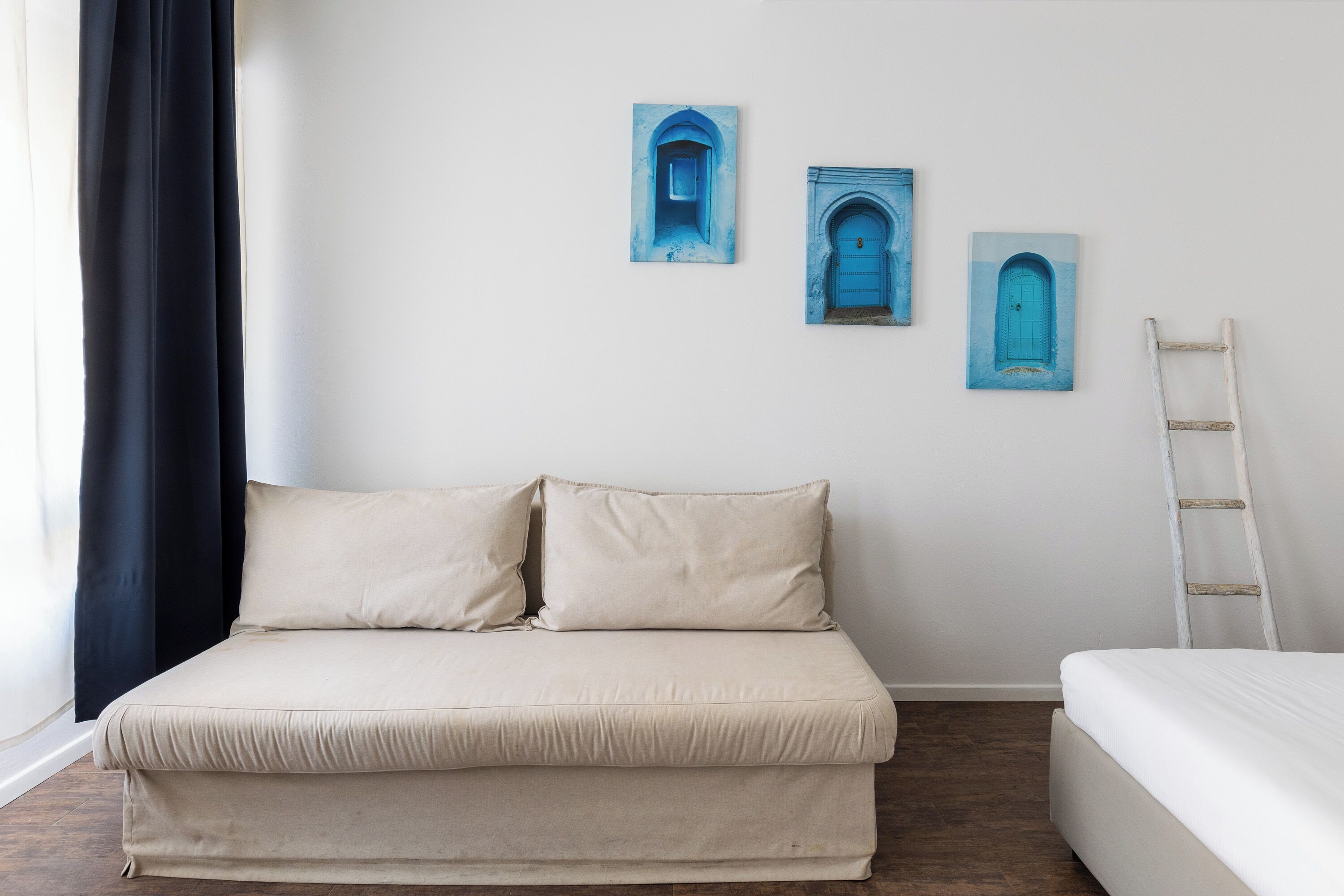 A room with a bed, a small table, and a ladder against the wall.