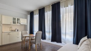 Ett modernt hotellrum med en matplats, en säng och ett stort fönster med gardiner.