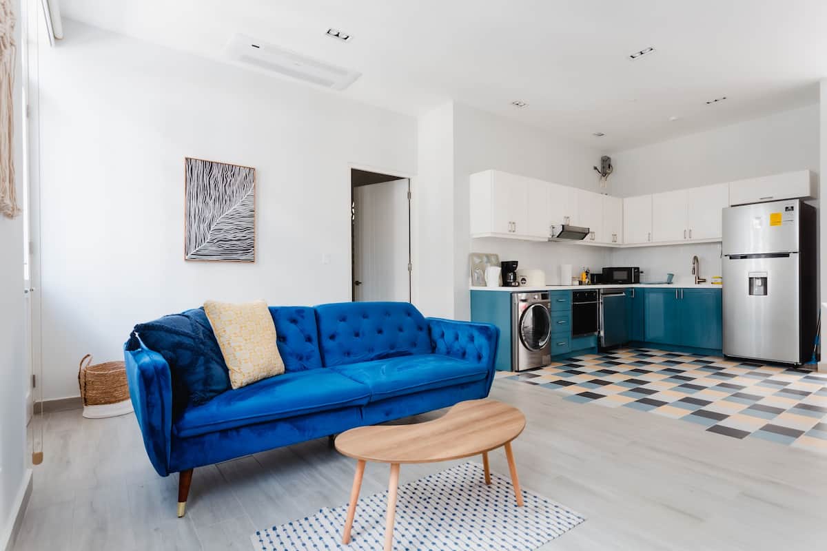 A modern apartment with a blue sofa, wooden coffee table, and a checkered floor.