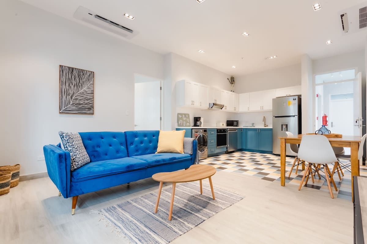 A modern living room with a blue sofa, a wooden coffee table, and a checkered floor.