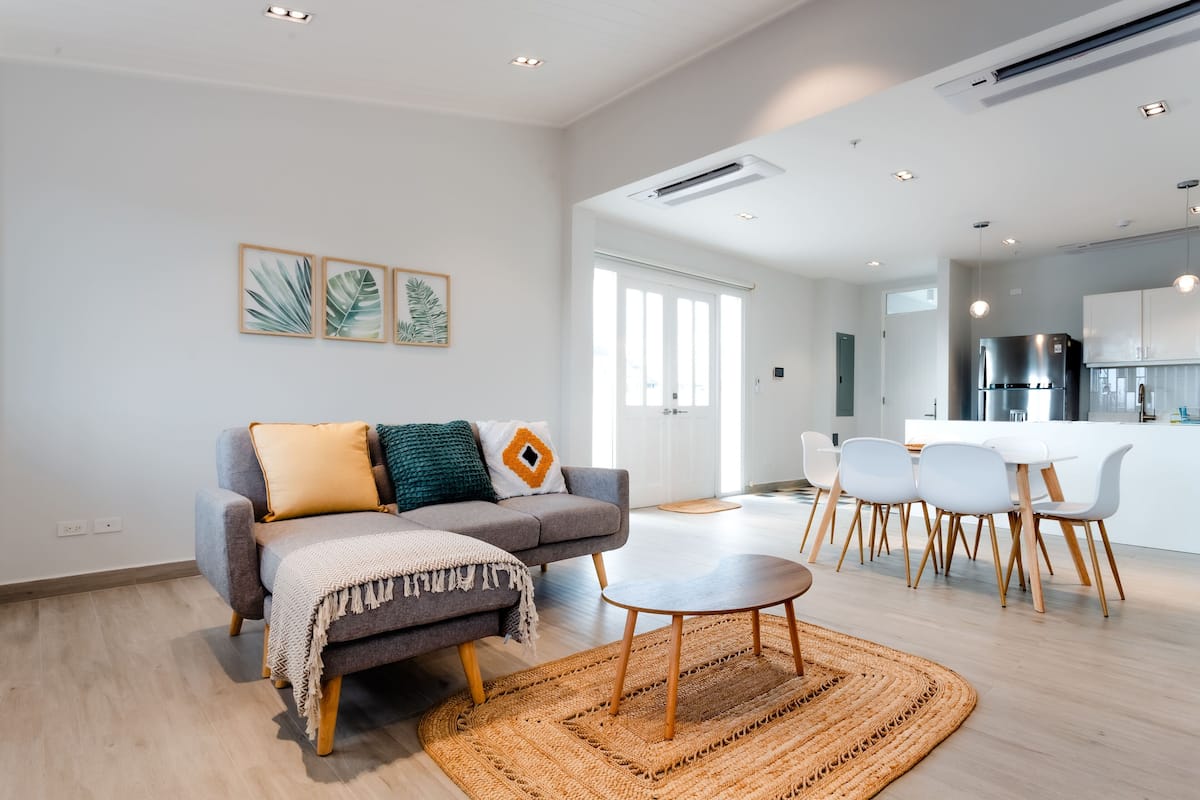 A modern living room with a grey sofa, a round coffee table, and a woven rug.