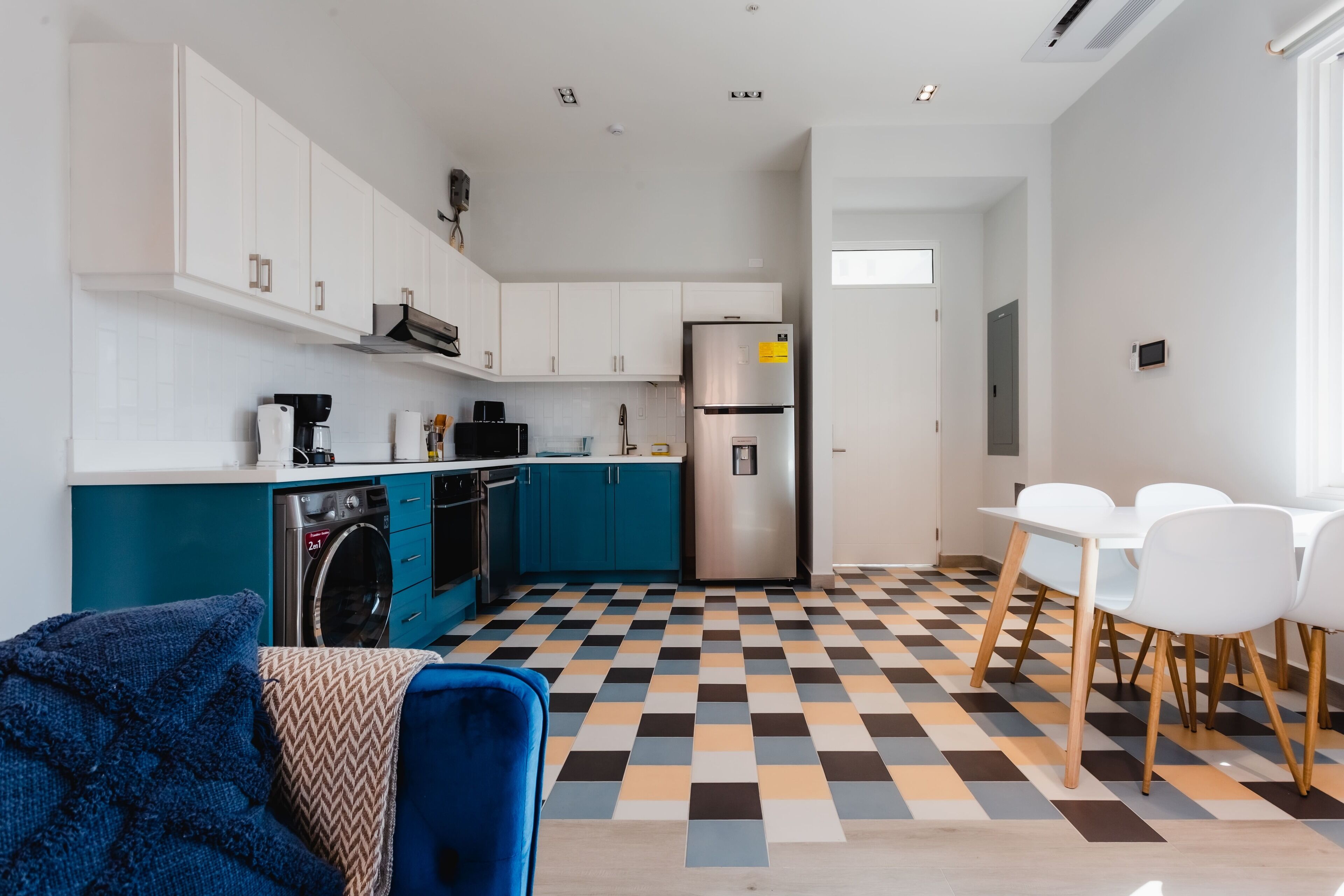 Eine moderne Küche mit weißen Schränken, einem Edelstahlkühlschrank und einer blauen Arbeitsplatte.