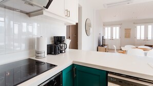 A modern kitchen with white cabinets, a black induction cooktop, and a coffee maker. - Casa Love by Wynwood House (Panama City)
