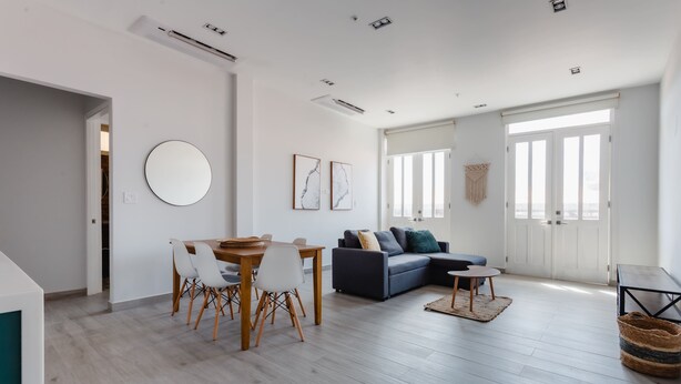 A modern living room with a dining area, a sofa, and a round mirror on the wall. - Casa Love by Wynwood House (Panama City)