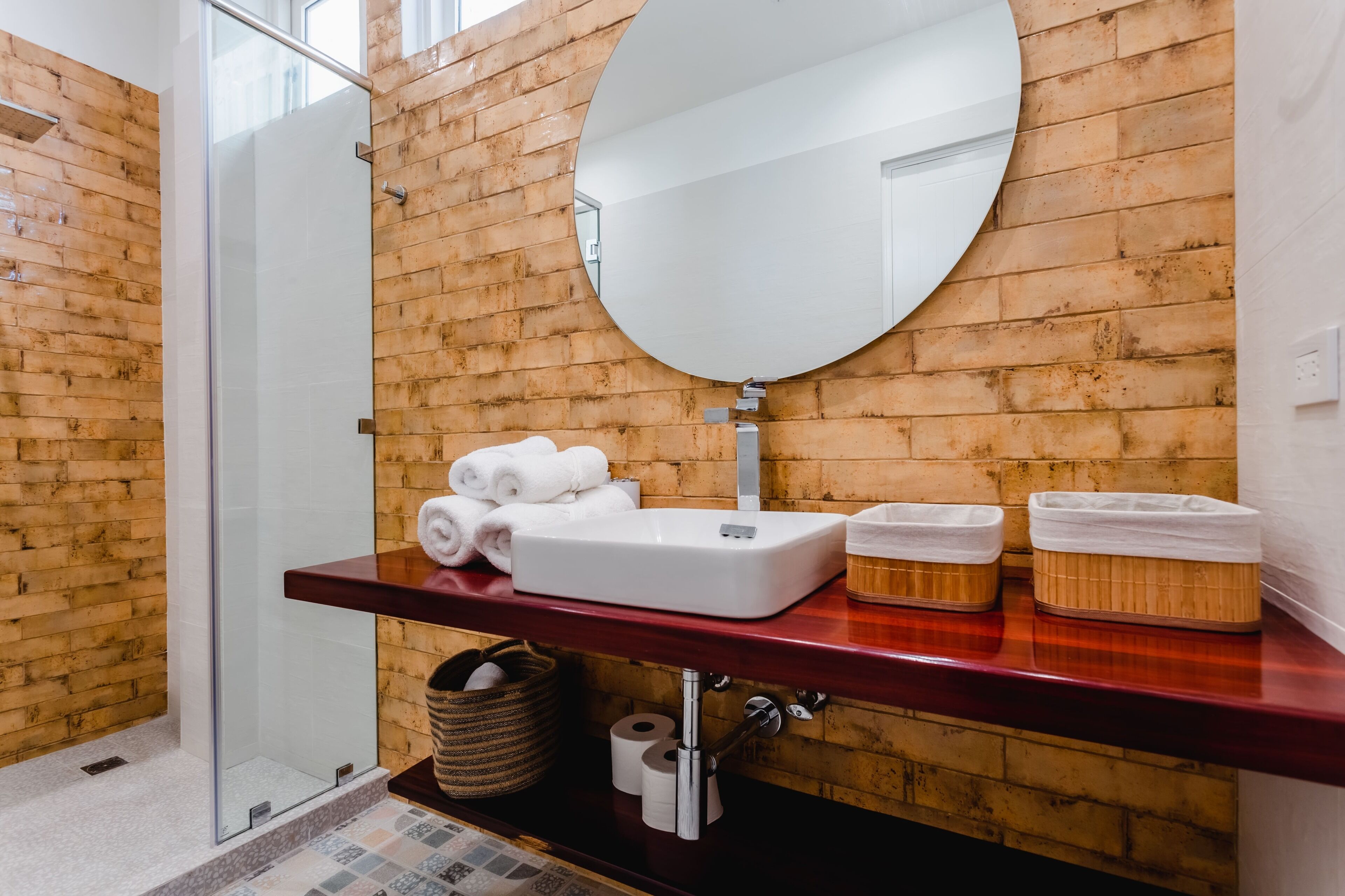 Une salle de bain avec un mur en bois, une cabine de douche en verre, un lavabo blanc et un miroir.