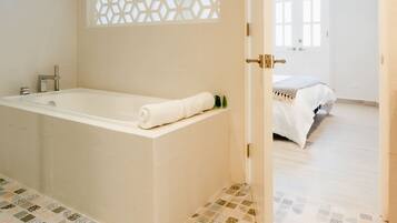A modern bathroom with a freestanding bathtub, a decorative lattice partition, and a patterned floor.