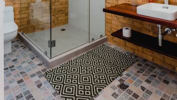 Ein modernes Badezimmer mit einer gläsernen Duschkabine, einem Holzbadezimmer-Möbel und einem Musterfußboden.