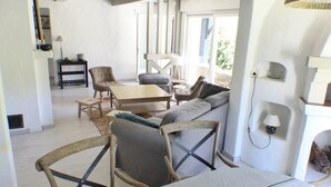 Een moderne woonkamer met een bank, stoelen, een salontafel en een eethoek.
