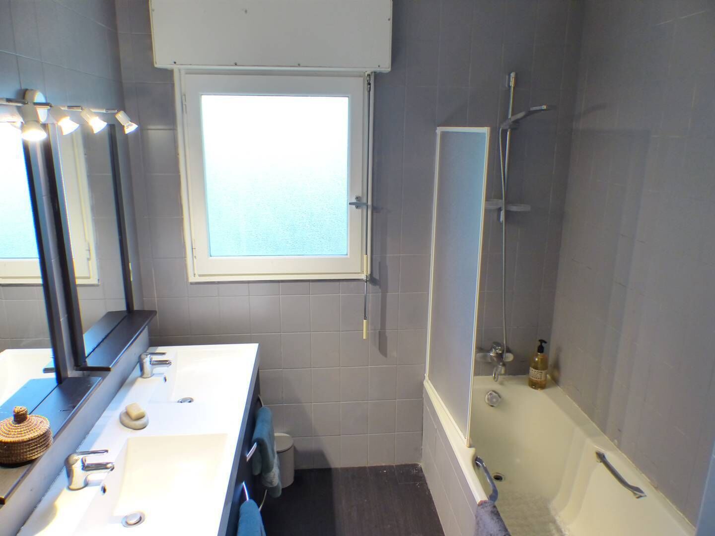 A bathroom with a bathtub, a window, and a mirror.