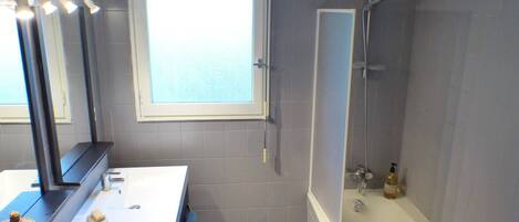 A bathroom with a bathtub, a window, and a mirror.