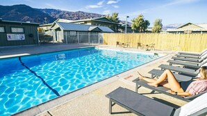 Una piscina con sillones de descanso y un cartel de 'No Diving', rodeada de edificios y montañas.