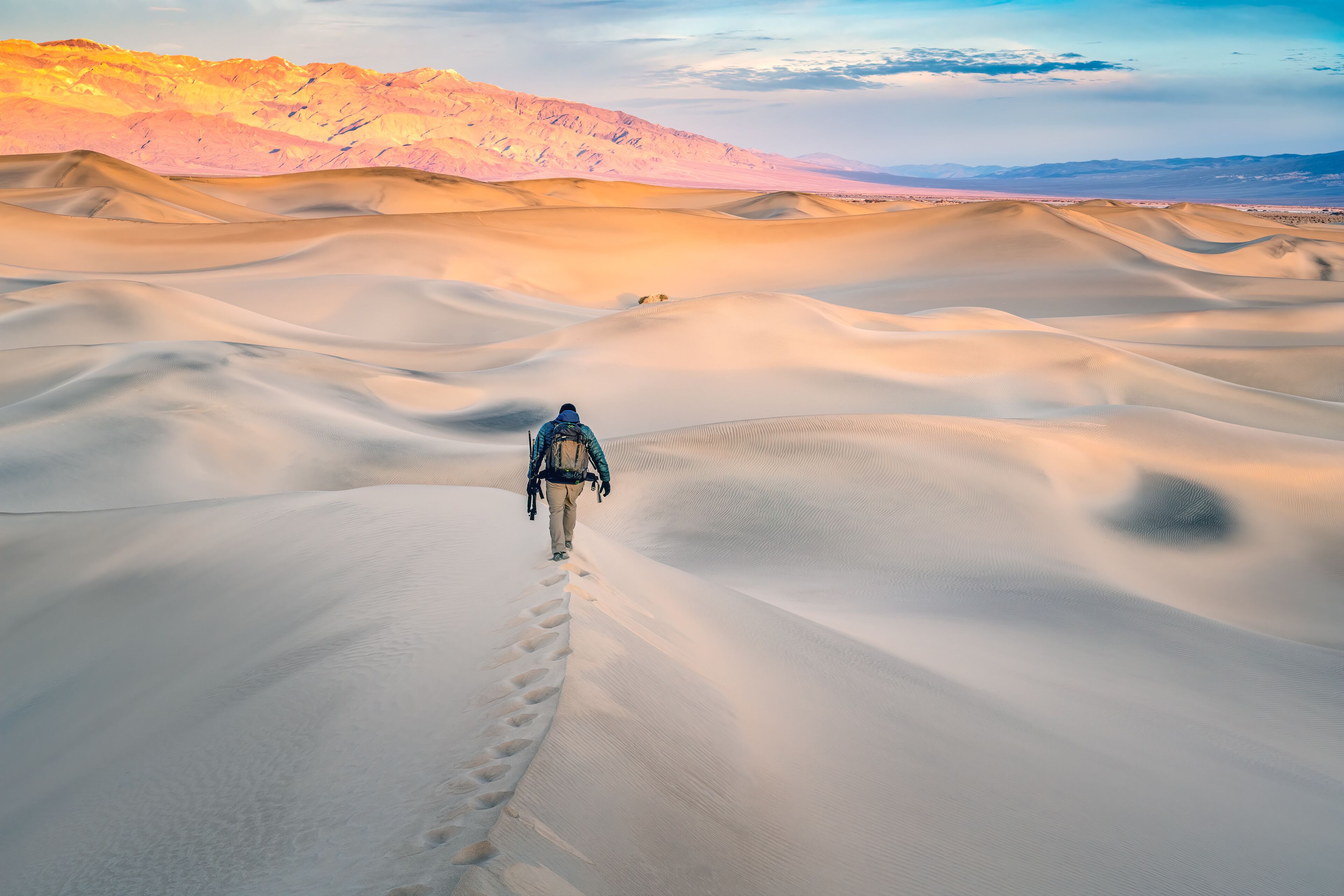 A person walking on a sandy path in a desert landscape.