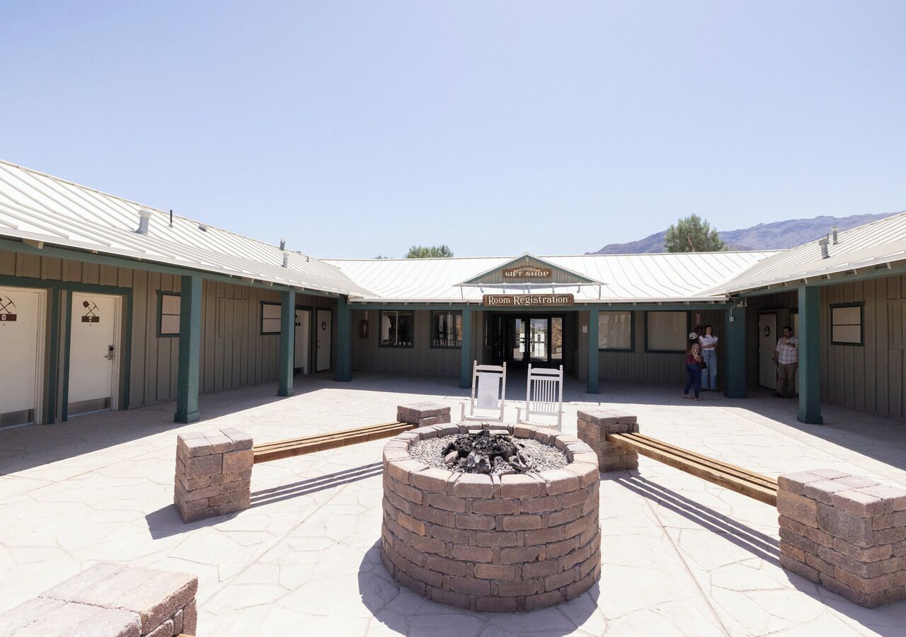 A hotel courtyard with a central fire pit, guest seating, and a gift shop.