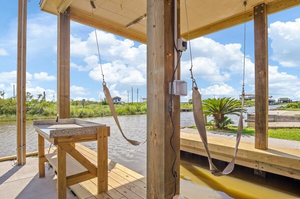 A wooden deck with a table and a hanging fish. - New Vacation Beach Home Fisherman's Dream (Bolivar Peninsula)