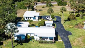 An aerial view of a residential area with two white houses, a paved driveway, and surrounding greenery. - Susannah Riverside Apartment - Tranquil getaway for 2 (Fort Pierce)
