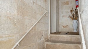 A stone staircase with a white handrail and a white vase with dried plants on the landing.
